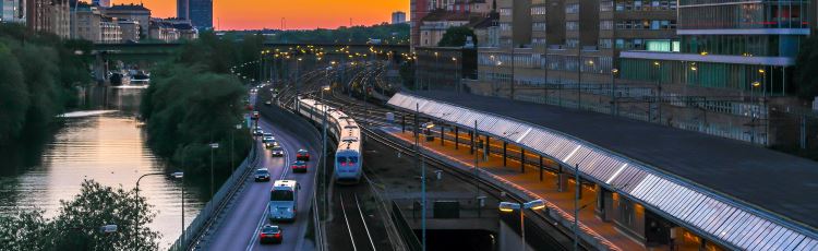 Biltrafik och tågtrafik i stadsmiljö i solnedgång. Foto: Mostphotos