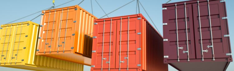 Containers som hänger i luften i olika färger mot en blå himmel