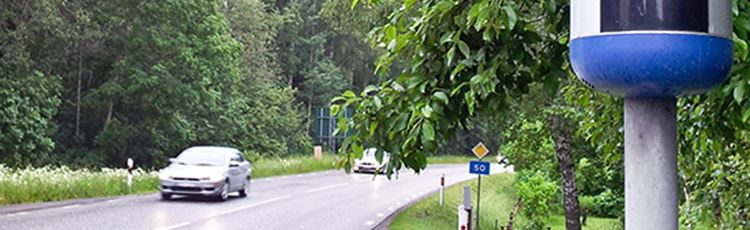 A speed limit camera next to the road.