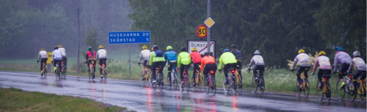 Cyklister som cyklar på rad på regnvåt asfaltsväg