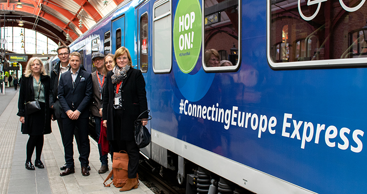 En grupp personer står på perrong intill EU-tåget The Connecting Europe Express.