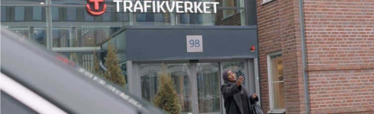 Kvinna framför Trafikverket Solna som tar en bild med sin telefon
