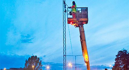 Person i skylift gör arbeten gör underhållsarbeten på vägbelysning i kvällsljus. Foto: Mikael Ullén