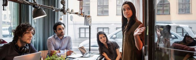 Bilden visar fyra personer som sitter samtal i ett arbetsmöte på ett kontor.