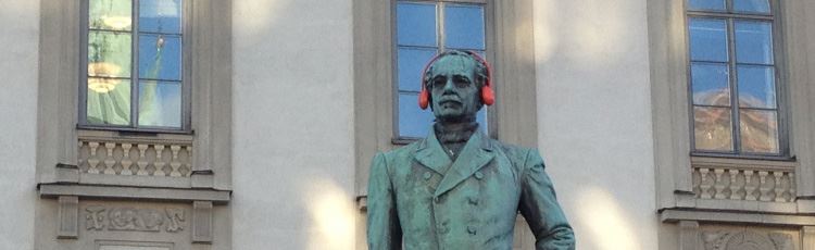 Staty av man med röda hörselkåpor på mannens huvud.