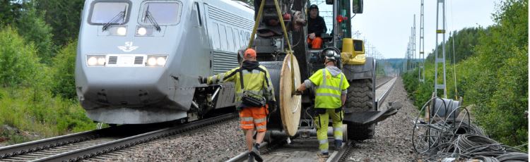 Arbetare på tågspår som drar kabel