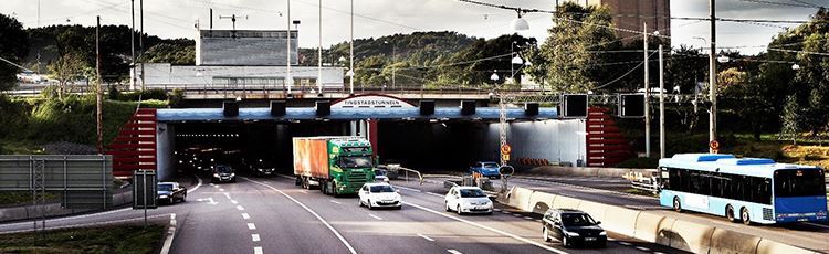 Tunnel opening with four files in each direction. Some cars, a truck and a bus are on their way out and into the tunnel, respectively. Photo: The Swedish Transport Administration.