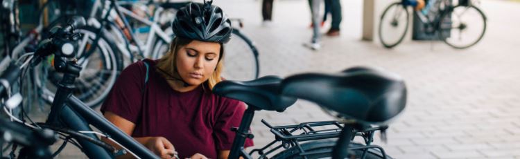 Kvinna låser upp cykel vid cykelställ