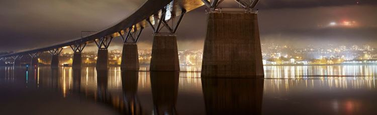 Sundsvallsbron om kvällen. Ljus från staden i horisonten.