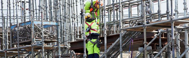 Personer i arbetskläder som klättrar på en byggställning.